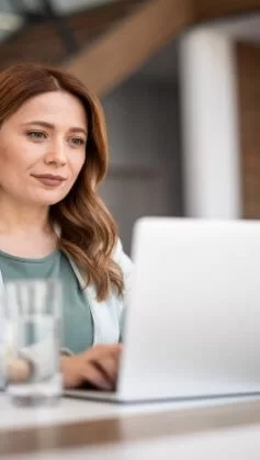 Mulher de roupas sociais trabalhando com marketing digital enquanto digita em um notebook.
