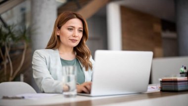 Mulher de roupas sociais trabalhando com marketing digital enquanto digita em um notebook.