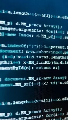 A imagem mostra um plano fechado de uma tela de computador com linhas de código, destacando-se em tons de azul e branco sobre um fundo escuro. O foco suave e o enquadramento criam uma atmosfera técnica e moderna, remetendo ao universo da programação, segurança da informação e engenharia de software. O conteúdo representa a complexidade lógica e sintática das linguagens de programação, simbolizando o processo de criação, análise e manutenção de sistemas digitais. É uma imagem que transmite concentração, tecnologia e inovação — conceitos centrais no desenvolvimento de soluções computacionais.