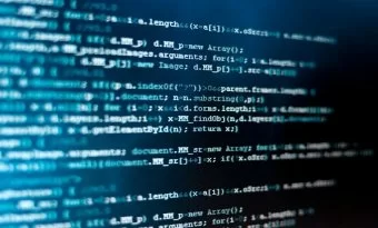 A imagem mostra um plano fechado de uma tela de computador com linhas de código, destacando-se em tons de azul e branco sobre um fundo escuro. O foco suave e o enquadramento criam uma atmosfera técnica e moderna, remetendo ao universo da programação, segurança da informação e engenharia de software. O conteúdo representa a complexidade lógica e sintática das linguagens de programação, simbolizando o processo de criação, análise e manutenção de sistemas digitais. É uma imagem que transmite concentração, tecnologia e inovação — conceitos centrais no desenvolvimento de soluções computacionais.