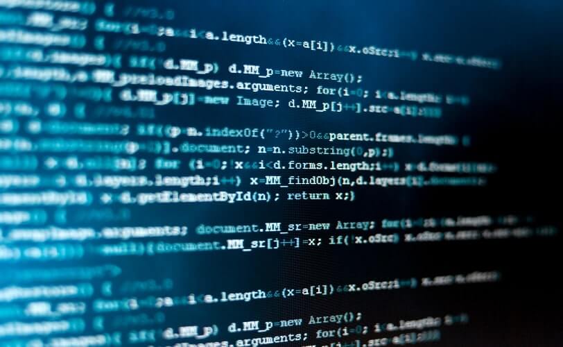 A imagem mostra um plano fechado de uma tela de computador com linhas de código, destacando-se em tons de azul e branco sobre um fundo escuro. O foco suave e o enquadramento criam uma atmosfera técnica e moderna, remetendo ao universo da programação, segurança da informação e engenharia de software. O conteúdo representa a complexidade lógica e sintática das linguagens de programação, simbolizando o processo de criação, análise e manutenção de sistemas digitais. É uma imagem que transmite concentração, tecnologia e inovação — conceitos centrais no desenvolvimento de soluções computacionais.
