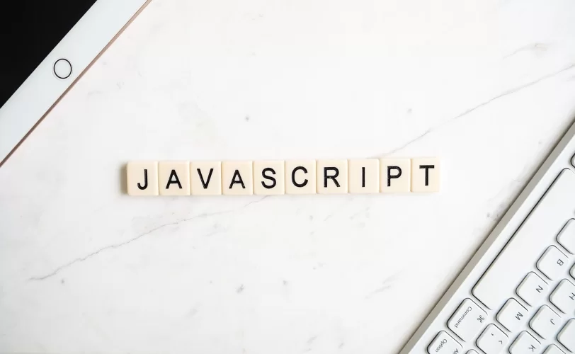 Imagem mostra a palavra Javascript centralizada e ao lado esquestdo um Ipad e ao direito um teclado.