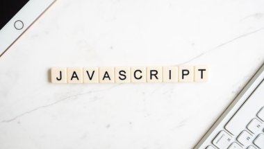 Na imagem há o nome 'javascript'. e nos cantos da imagem há um teclado de computador e no outro um ipad.