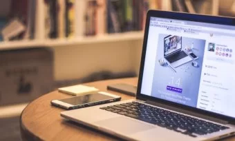 A imagem mostra uma mesa e sobre ela há um notebook e celular.