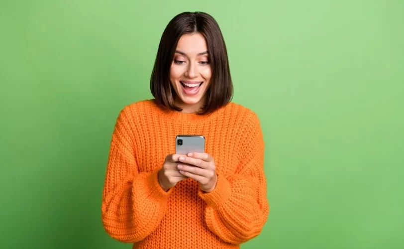 Mulher sorrindo olhando para o smartphone. 