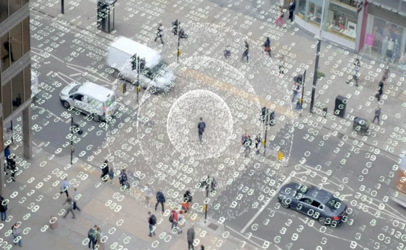 a imagem mostra uma rua movimentada por carros e pedestres e sobre essa imagem há números binários. 