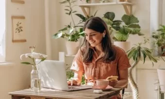 mulher trabalhando feliz em frente a um notebook.