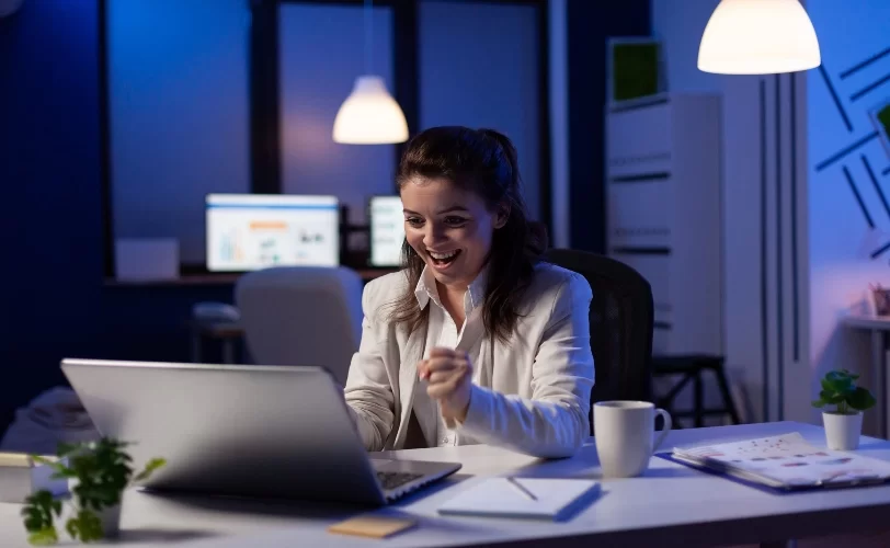 mulher executiva feliz frente a um notebook.