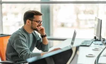 Homem feliz frente a computador.