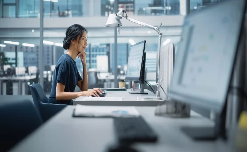 Mulher sentada em frente a um computador em um escritório. 