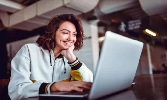 Mulher sorrindo e olhando para um notebook