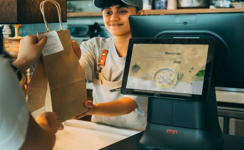 mulher entregando uma compra ao cliente em um caixa 