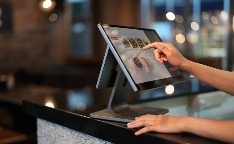 a imagem mostra uma mulher selecionando opções para comprar em um tablet no ponto de venda. 