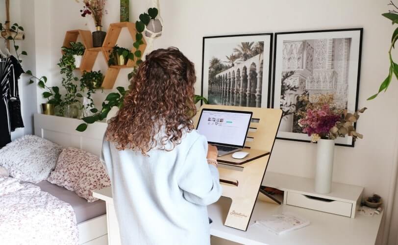 mulher trabalhando em pé em frente a um notebook em um espaço aconchegante de casa. 