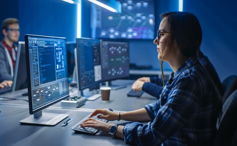 Mulher desenvolvedore frente a uma tela de computador. 