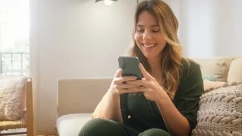 A imagem mostra uma mulher loira mexendo no celular. Ela provavelmente foi impactada pela publicação de uma empresa que pensou em como crescer no Instagram, aplicando algumas técnicas para aumentar alcance e engajamento.
