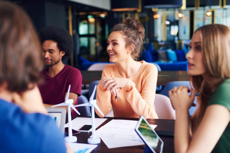 Quatro pessoas em volta de uma mesa de reuniões empresarial, conversando e sorrindo. A imagem faz parte do artigo sobre responsabilidade corporativa. 