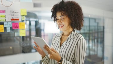 Mulher sorrindo e olhando para um tablet. A imagem compõe o conteúdo sobre extensões para o google chrome.