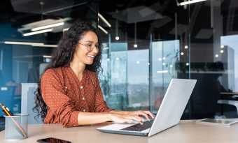 Mulher em escritório mexendo em seu notebook