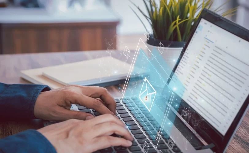 Homem digitando em um notebook. E há uma imagem 3D sobre o teclado de um ícone de e-mail. A imagem faz parte do conteúdo sobre SPAM em campanhas de e-mail marketing. 