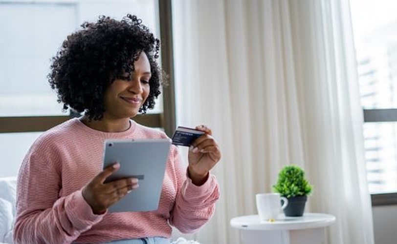 mulher usando cartão de crédito para realizar compra online após ser impactada pelos gatilhos mentais
