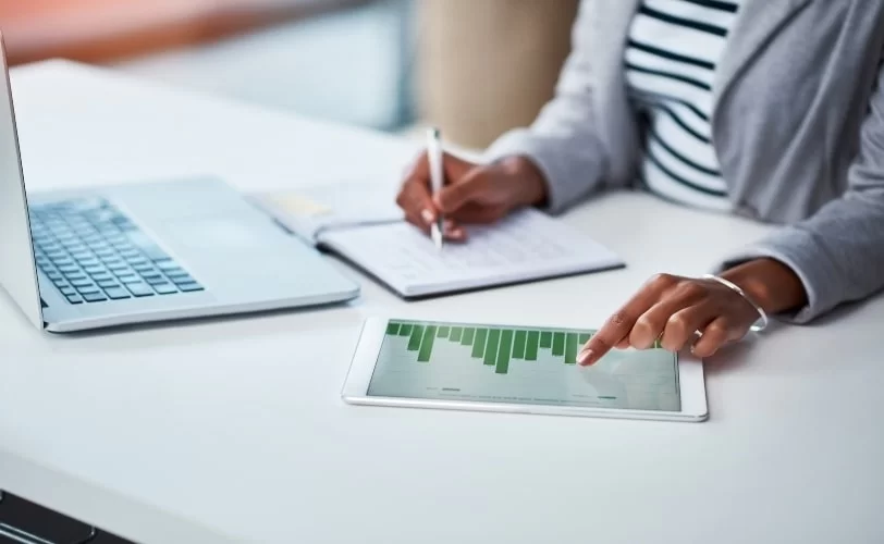 mulher calculando a frequência absoluta usando um notebook e um tablet