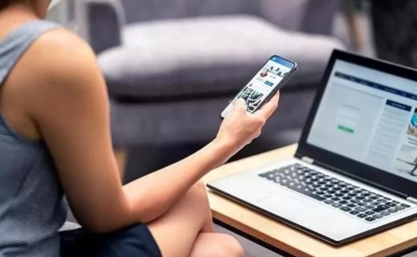 Homem com um celular na mão e um notebook a sua frente conferindo sobre as diretrizes do Google de E-E-A-T. 