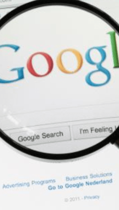 A imagem mostra uma lupa sobre o logo do Google na página de busca da empresa.