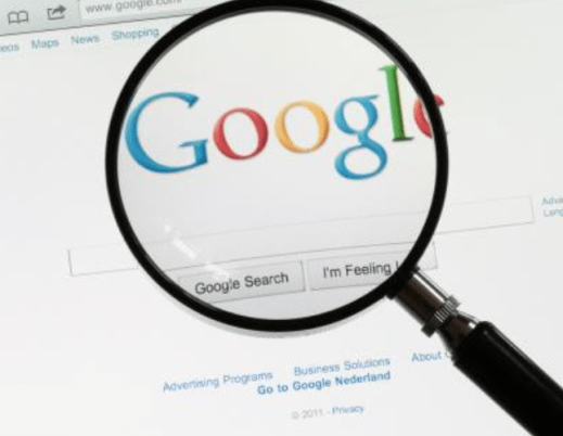 A imagem mostra uma lupa sobre o logo do Google na página de busca da empresa.