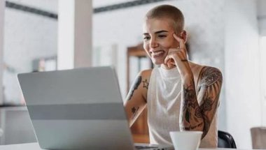Mulher desenvolvedora em frente ao seu notebook. A imagem compõe o conteúdo sobre ambiente de desenvolvimento integrado.