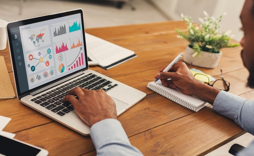 Homem em frente a um computador, com dashboards para dar ênfase a importância dos dados nas estratégias de marketing de influência.  