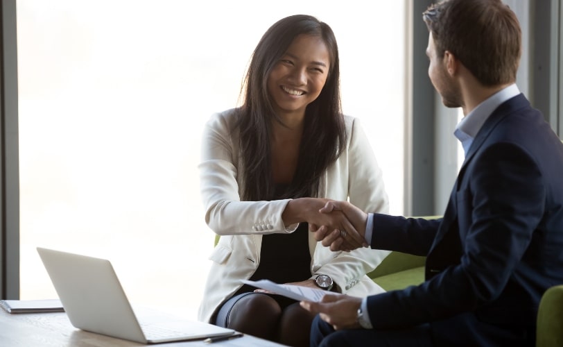 Mulher apertando a mão de um rapaz, denotando um fechamento de parcerias para marketing de influência. 