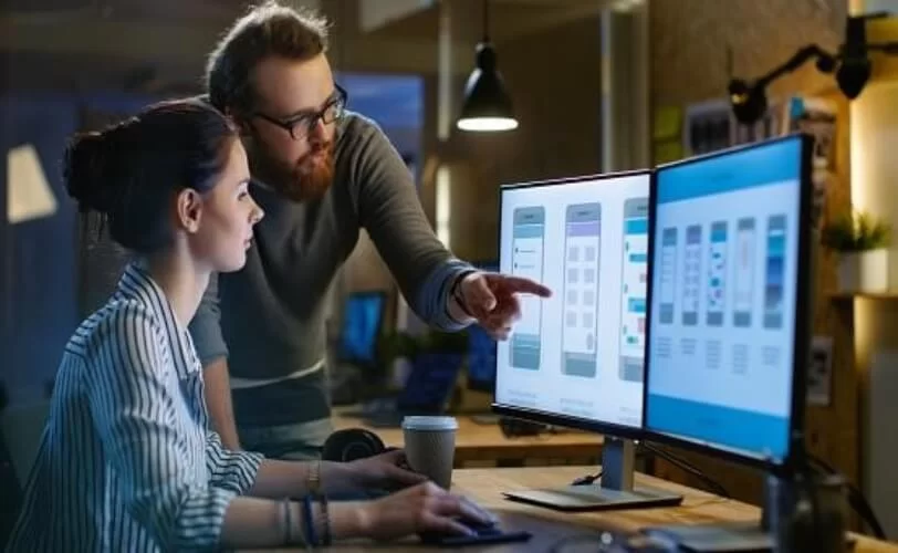 homem e mulher de frente a telas de computadores analisando imagens 