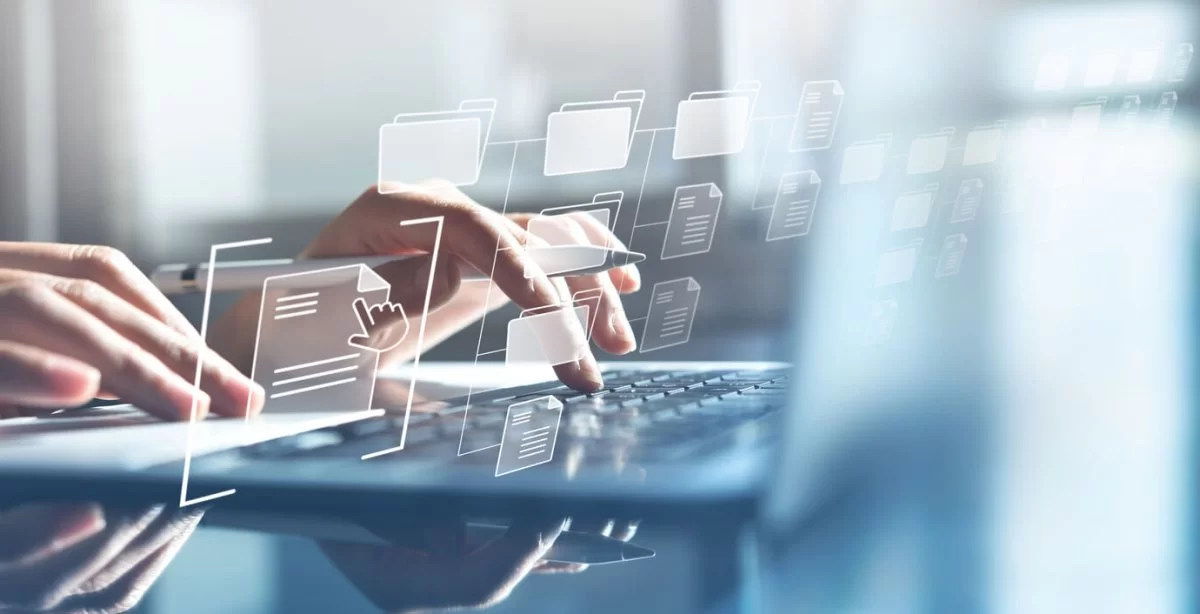 Mãos digitando em laptop. Há uma estrutura de pastas e arquivos sobre elas