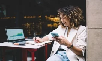 Mulher mexendo no celular e fazendo anotações