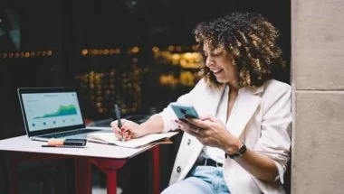 Mulher mexendo no celular e fazendo anotações