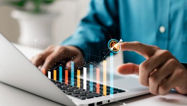 Pessoa usando laptop. Há um gráfico sobre o teclado. O rosto dela não aparece