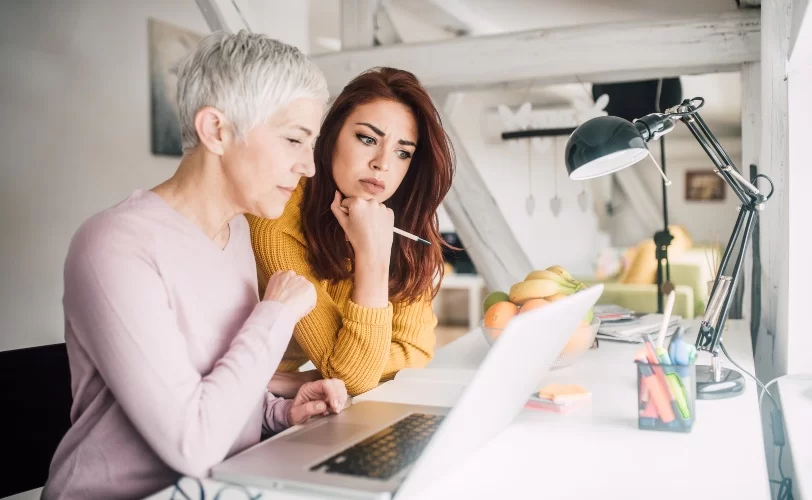 Duas mulheres analisando o conteúdo na tela de um laptop