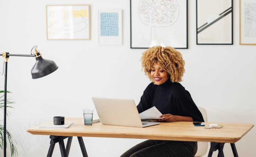 Mulher sorrindo diante de um notebook, em um ambiente minimalista