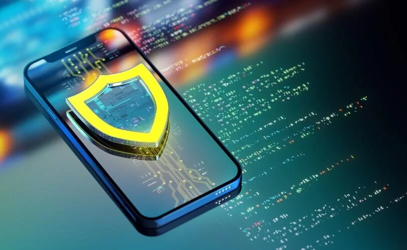 Símbolo de segurança sobre celular que, por sua vez, está sobre uma tela com códigos