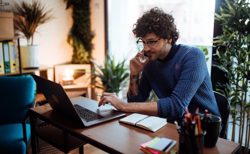 Homem a trabalhar como freelancer online, no celular e no computador