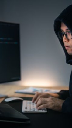 homem no computador escrevendo código malicioso