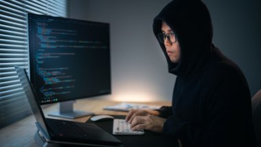 homem no computador escrevendo código malicioso