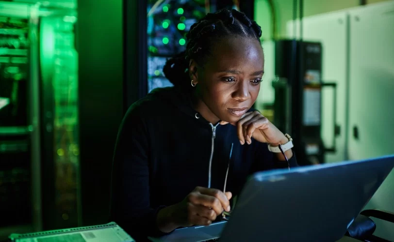 Programadora utilizando laptop em sala de servidor