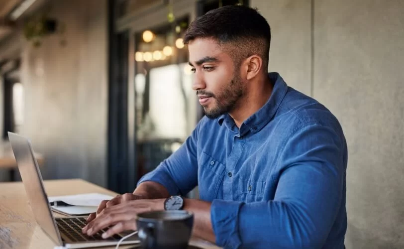 homem usando computador e tomando café