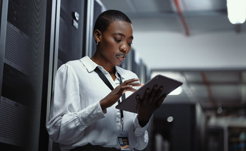 Mulher trabalhando em tablet dentro de sala de servidor
