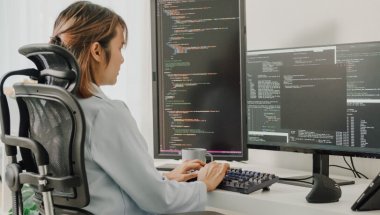 Desenvolvedora trabalhando com múltiplos monitores