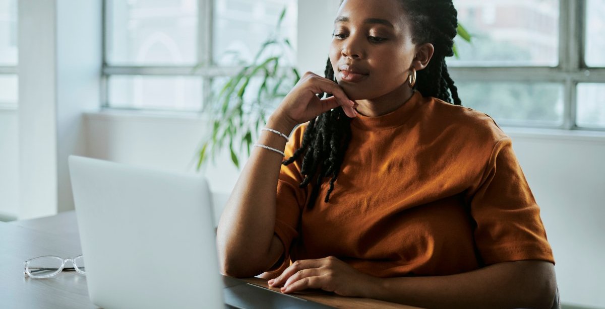 A imagem mostra uma mulher negra em um escritório com uma expressão pensativa. Ela está avaliando como aplicar os recursos da CDN para melhorar o desempenho do site de sua empresa.