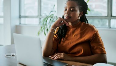 A imagem mostra uma mulher negra em um escritório com uma expressão pensativa. Ela está avaliando como aplicar os recursos da CDN para melhorar o desempenho do site de sua empresa.