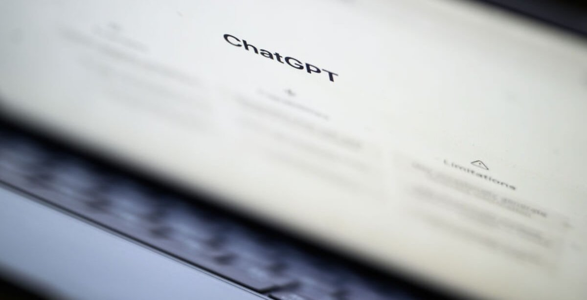 A imagem mostra um notebook semiaberto, com a tela principal do ChatGPT aberta. O logo do serviço de Inteligência Artificial está em destaque, enquanto os demais elementos aparecem borrados na tela.